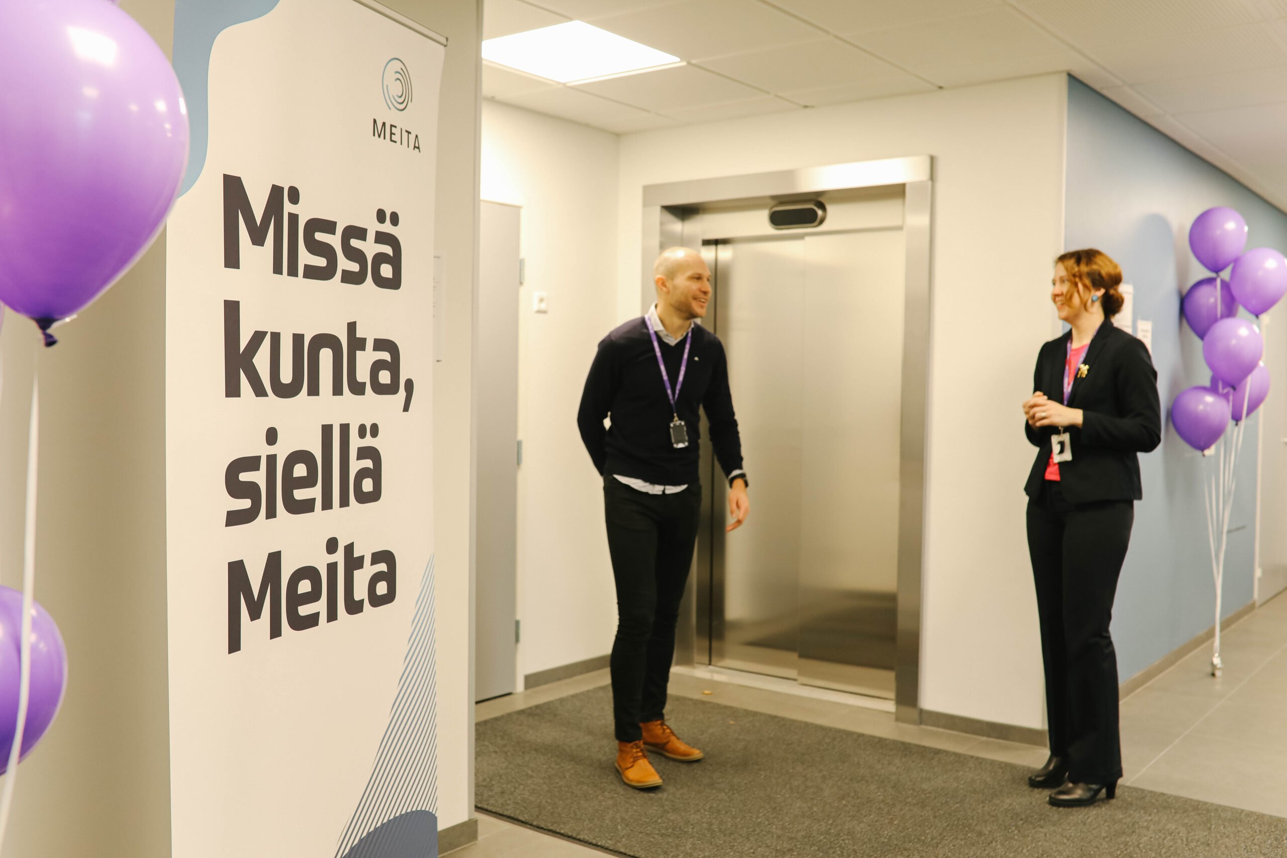 Tässä kuvassa on kaksi meitalaisia ja Meitan roll-up Mikkelin toimiston aulassa